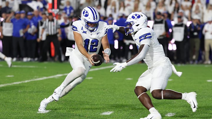 Sep 21, 2024; Provo, Utah, USA; Brigham Young Cougars quarterback Jake Retzlaff (12) fakes a handoff to running back Miles Davis (4) against the Kansas State Wildcats during the first quarter at LaVell Edwards Stadium.