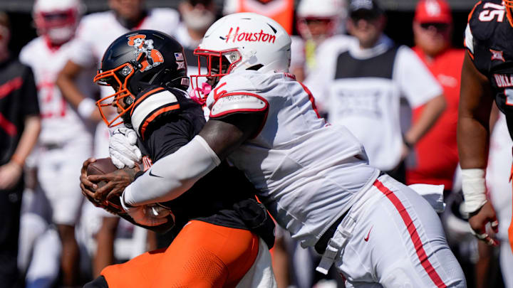 Houston Cougars defensive lineman Carlos Allen (5) brings down Oklahoma State Cowboys quarterback Sam Jackson V (18) during a college football game between the Oklahoma State Cowboys (OSU) and the Houston Cougars at Boone Pickens Stadium in Stillwater, Okla., Saturday, Oct. 11, 2025. Houston won 39-17. Houston Cougars defensive lineman Carlos Allen (5) brings down Oklahoma State Cowboys quarterback Sam Jackson V (18) during a college football game between the Oklahoma State Cowboys (OSU) and the Houston Cougars at Boone Pickens Stadium in Stillwater, Okla., Saturday, Oct. 11, 2025. Houston won 39-17.