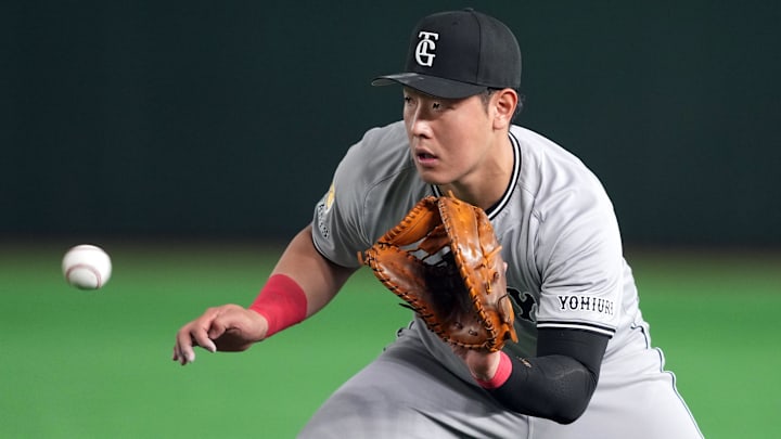 Mar 15, 2025; Bunkyo, Tokyo, Japan; Yomiuri Giants first baseman Kazuma Okamoto (25) fields a ground ball against the Los Angeles Dodgers during the fifth inning at Tokyo Dome. Mandatory Credit: Darren Yamashita-Imagn Images