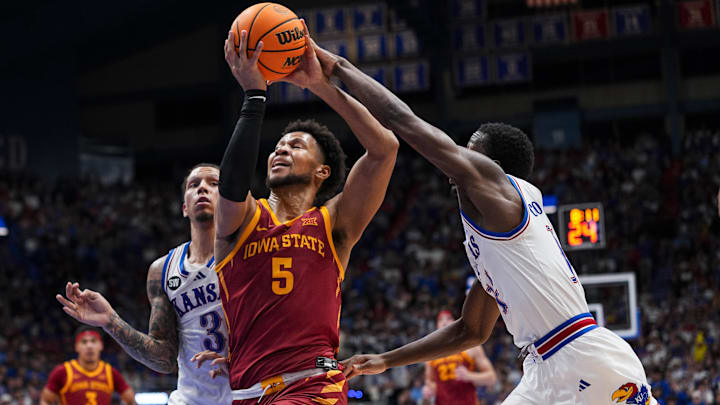 Jan 13, 2026; Lawrence, Kansas, USA; Iowa State Cyclones forward Joshua Jefferson (5) drives against Kansas Jayhawks guard Tre White (3) and guard Melvin Council Jr. (14) during the first half at Allen Fieldhouse.