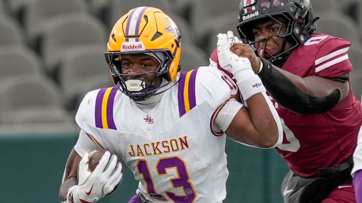 Dec 5, 2025; Birmingham, AL, USA; Jackson's EJ Crowell (13) breaks a tackle by Anniston's Dariontae Brooks Jr. (0) at Protective Life Stadium in the AHSAA 4A State Championship game.