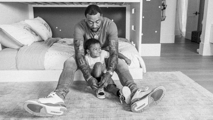 John Wall sits on his son, Amir's, bed while helping him tie his shoe during a photoshoot for Tommy Oliver's "Father Noir." John Wall sits on his son, Amir's, bed while helping him tie his shoe during a photoshoot for Tommy Oliver's "Father Noir."