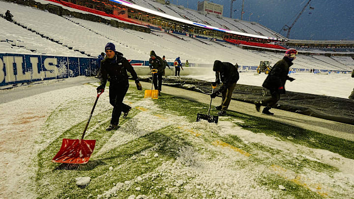 Workers shovel snow off to the sidelines as the tarp covering the field slowly gets pulled back before tonight's Bills home game against the San Francisco 49ers in Orchard Park on Dec. 1, 2024.
