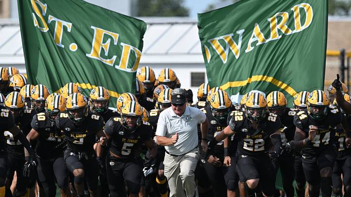 St. Edward football head coach Tom Lombardo leads the Eagles onto the field before a game against Elder on September 10, 2022. 