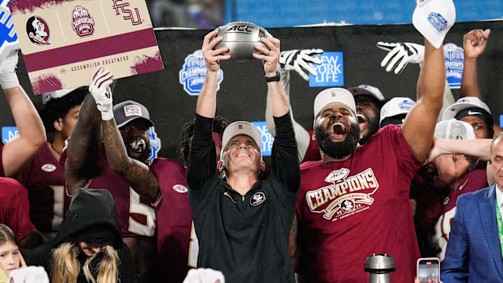 Dec 2, 2023; Charlotte, NC, USA; Florida State Seminoles head coach Mike Norvell raises the ACC Championship trophy with his players after the game against the Louisville Cardinals at Bank of America Stadium. Mandatory Credit: Jim Dedmon-Imagn Images