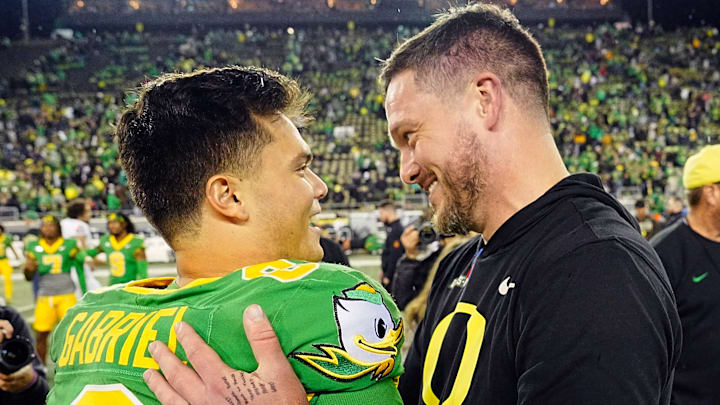 Oregon quarterback Dillon Gabriel, left, and coach Dan Lanning embrace after defeating Maryland at Autzen Stadium.