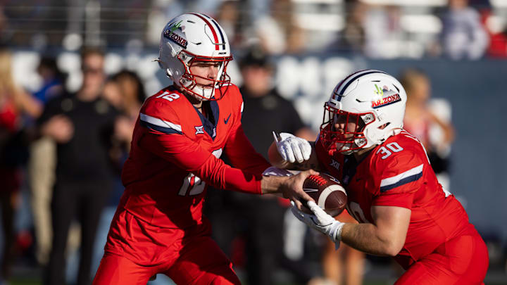 Oct 19, 2024; Tucson, Arizona, USA; Arizona Wildcats quarterback Cole Tannenbaum (12) hands the ball off to running back Kayden Luke (30) against the Colorado Buffalos at Arizona Stadium. 