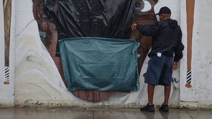 A worker examines a defaced mural of Jackie Robinson in Miami.