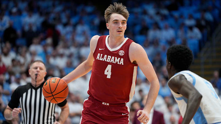 Dec 4, 2024; Chapel Hill, North Carolina, USA; Alabama Crimson Tide forward Grant Nelson (4) with the ball as North Carolina Tar Heels guard Drake Powell (9) defends in the first half at Dean E. Smith Center. Mandatory Credit: Bob Donnan-Imagn Images