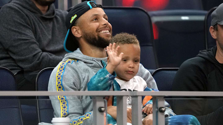 Golden State Warriors guard Stephen Curry (30) sits in the stands with son Canon during the second quarter against the Sacramento Kings at the California Summer League at Chase Center.