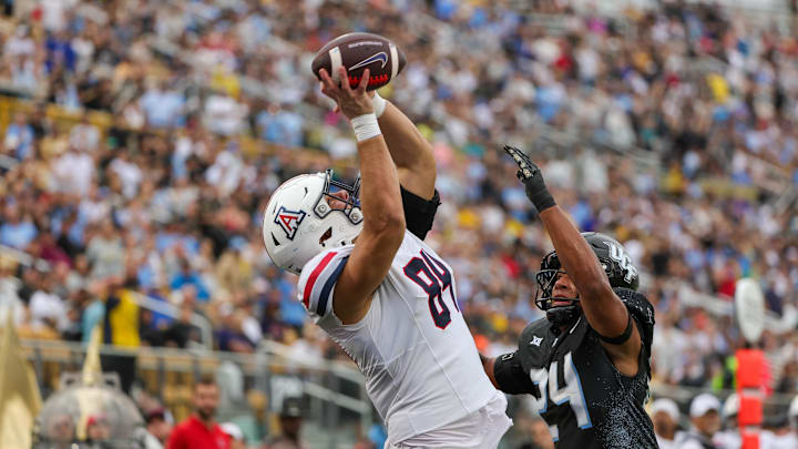 Nov 2, 2024; Orlando, Florida, USA; Arizona Wildcats tight end Sam Olson (84) catches a touchdown pass against UCF Knights linebacker Xe'ree Alexander (24) during the second quarter at FBC Mortgage Stadium. Mandatory Credit: Mike Watters-Imagn Images Nov 2, 2024; Orlando, Florida, USA; Arizona Wildcats tight end Sam Olson (84) catches a touchdown pass against UCF Knights linebacker Xe'ree Alexander (24) during the second quarter at FBC Mortgage Stadium. Mandatory Credit: Mike Watters-Imagn Images