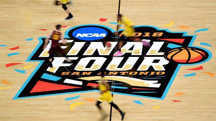 Players from the Loyola Ramblers and Michigan Wolverines run across the center court logo Players from the Loyola Ramblers and Michigan Wolverines run across the center court logo