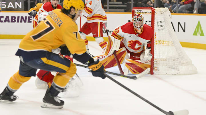 Dec 2, 2025; Nashville, Tennessee, USA;  Calgary Flames goaltender Dustin Wolf (32) blocks the shot of Nashville Predators right wing Luke Evangelista (77) during the third period at Bridgestone Arena. Mandatory Credit: Steve Roberts-Imagn Images
