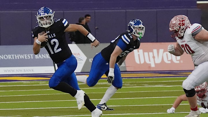 MMCRU's quarterback Eli Harpenau (12) runs with the ball for a first down against MMCRU during the first quarter in the Class A state football championship on Nov. 20, 2025, at UNI Dome in Cedar Falls, Iowa.