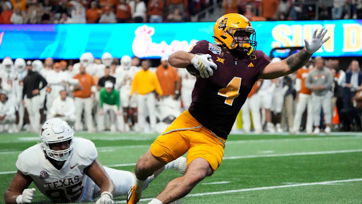 Arizona State running back Cam Skattebo (4) escapes a tackle by Texas defensive lineman Alfred Collins (95) during the fourth quarter in the Chick-fil-A Peach Bowl in Atlanta on Wednesday, Jan. 1, 2025.