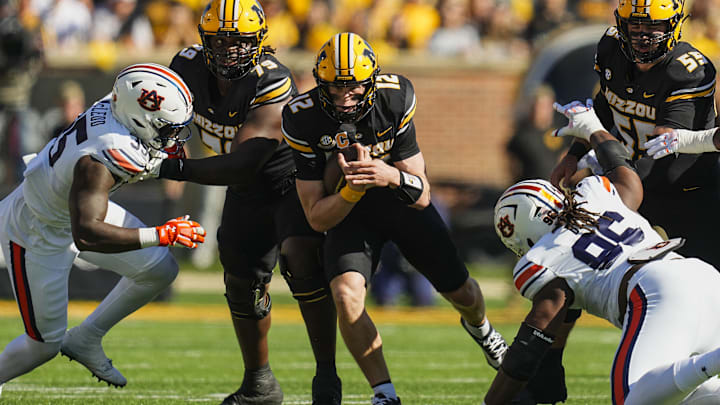 Oct 19, 2024; Columbia, Missouri, USA; Missouri Tigers quarterback Brady Cook (12) runs the ball against Auburn Tigers nose tackle Jalen McLeod (35) and defensive lineman Philip Blidi (96) during the first half at Faurot Field at Memorial Stadium. Mandatory Credit: Jay Biggerstaff-Imagn Images
