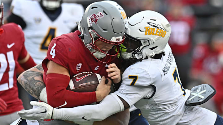 Oct 25, 2025; Pullman, Washington, USA; Washington State Cougars quarterback Zevi Eckhaus (4) is tackled by Toledo Rockets safety Emmanuel McNeil-Warren (7) in the second half at Gesa Field at Martin Stadium. Mandatory Credit: James Snook-Imagn Images