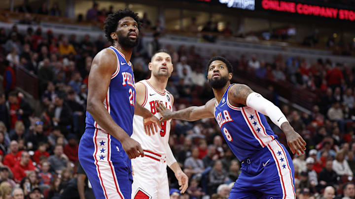Dec 8, 2024; Chicago, Illinois, USA; Philadelphia 76ers center Joel Embiid (21) and forward Paul George (8) defend against Chicago Bulls center Nikola Vucevic (9) during the first half at United Center. Mandatory Credit: Kamil Krzaczynski-Imagn Images