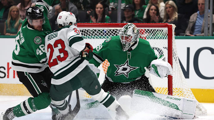 Dec 27, 2024; Dallas, Texas, USA; Dallas Stars defenseman Ilya Lyubushkin (46) defends Minnesota Wild center Marco Rossi (23) as goaltender Jake Oettinger (29) protects the goal in the first period at American Airlines Center. Mandatory Credit: Tim Heitman-Imagn Images