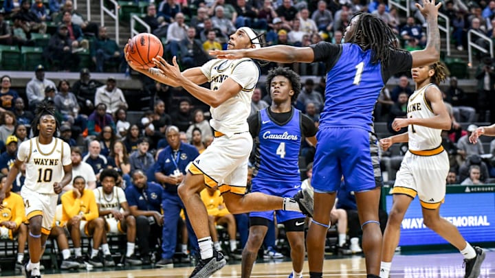 Wayne Memorial's Carlos Medlock Jr., left, scores against Flint Carman-Ainsworth during the fourth quarter in the Division 1 state semifinal on Friday, March 14, 2025, at the Breslin Center in East Lansing.