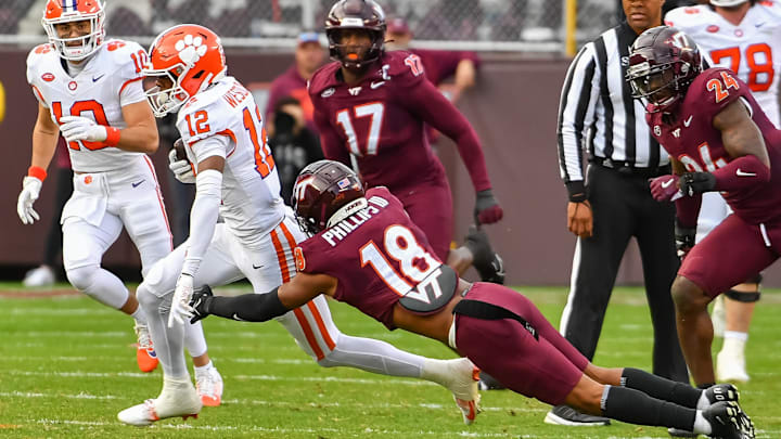Nov 9, 2024; Blacksburg, Virginia, USA;  .Virginia Tech Hokies safety Mose Phillips III (18) dives to tackle Clemson Tigers cornerback Corian Gipson (12) during the first quarter at Lane Stadium. Mandatory Credit: Brian Bishop-Imagn Images