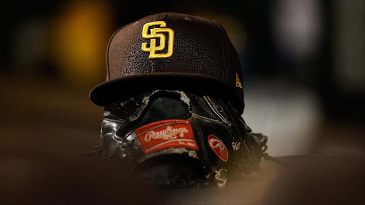 Jun 17, 2022; Denver, Colorado, USA; A detail view of a San Diego Padres hat on a glove in the dugout in the ninth inning against the Colorado Rockies at Coors Field. Mandatory Credit: Isaiah J. Downing-Imagn Images