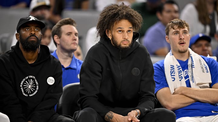 Oct 6, 2025; Fort Worth, Texas, USA; Dallas Mavericks guard Kyrie Irving, center Dereck Lively II, and forward Cooper Flaggwatch the game against the Oklahoma City Thunder.