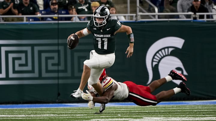 Nov 29, 2025; Detroit, Michigan, USA; Michigan State quarterback Alessio Milivojevic (11) breaks a tackle from Maryland defensive lineman Sidney Stewart (29) in the third quarter at Ford Field. Mandatory Credit: Brendan Mullin-Imagn Images