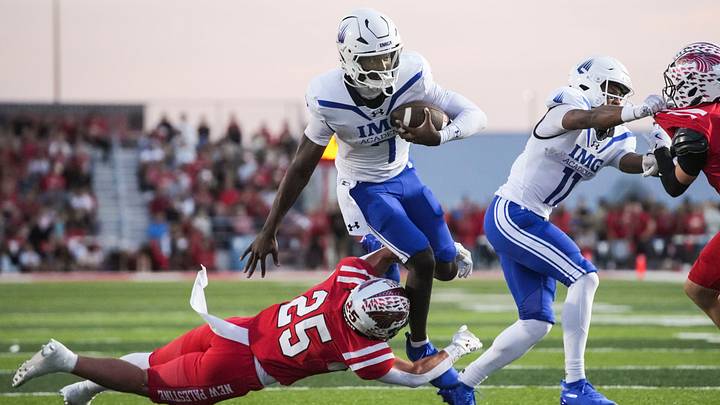 New Palestine Dragons Waynee Estes (25) attempts to tackle IMG Academy Ascenders Jayden Wade (7) as he runs the ball Friday, Oct. 9, 2026, during the first half of a game at New Palestine High School in New Palestine, Ind.