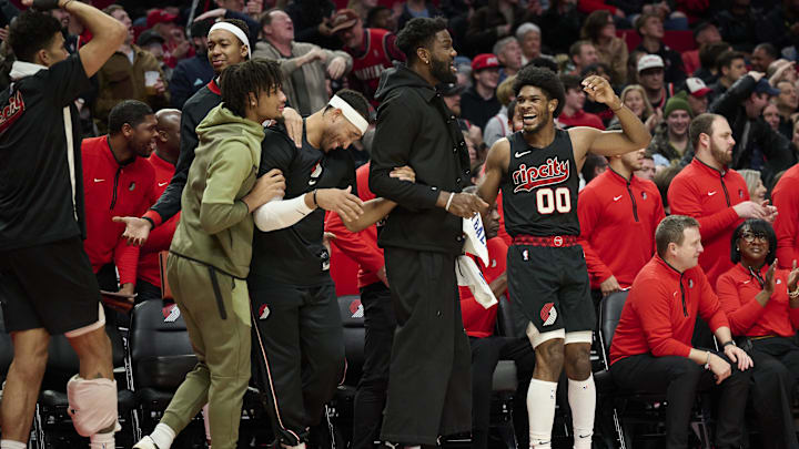 Dec 29, 2023; Portland, Oregon, USA; Portland Trail Blazers guard Scoot Henderson (00), right, reacts with teammates, from left, guard Shaedon Sharpe (17), forward Ish Wainright (23), and center Deandre Ayton (2) after a play during the second half against the San Antonio Spurs at Moda Center. Mandatory Credit: Troy Wayrynen-Imagn Images
