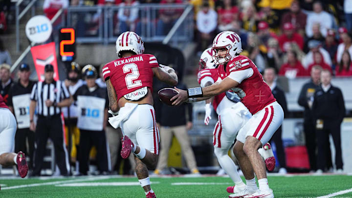 Oct 11, 2025; Madison, Wisconsin, USA; Wisconsin Badgers quarterback Hunter Simmons (15) hands the ball off to wide receiver Trech Kekahuna (2) in the first quarter against the Iowa Hawkeyes at Camp Randall Stadium. Mandatory Credit: Ross Harried-Imagn Images Oct 11, 2025; Madison, Wisconsin, USA; Wisconsin Badgers quarterback Hunter Simmons (15) hands the ball off to wide receiver Trech Kekahuna (2) in the first quarter against the Iowa Hawkeyes at Camp Randall Stadium. Mandatory Credit: Ross Harried-Imagn Images