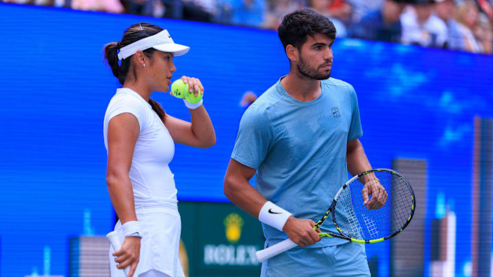 August 19, 2025; Emma Raducanu and Carlos Alcaraz talk strategy during a mixed doubles match against Jessica Pegula and Jack Draper at the 2025 US Open at USTA Billie Jean King National Tennis Center.