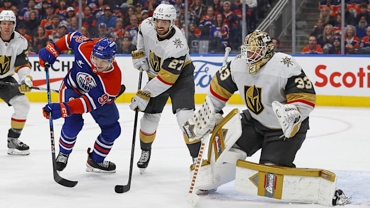 Dec 14, 2024; Edmonton, Alberta, CAN; Edmonton Oilers forward Vasily Podkolzin (92) and Vegas Golden Knights defensemen Shea Theodore (27) look for a loose puck in front of  goaltender Adin Hill (33) during the third period at Rogers Place. Mandatory Credit: Perry Nelson-Imagn Images