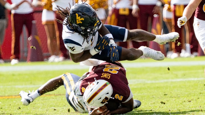 West Virginia Mountaineers Fred Perry (5) jumps over Arizona State Sun Devils Jeff Sims (2) and West Virginia Mountaineers Jordan Walker (4) during a game at Mountain America Stadium in Tempe on Nov. 15, 2025.