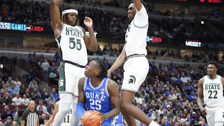 Nov 14, 2023; Chicago, Illinois, USA; Michigan State Spartans guard Tre Holloman (5) defends Duke Blue Devils forward Mark Mitchell (25) during the first half at United Center. Mandatory Credit: David Banks-Imagn Images