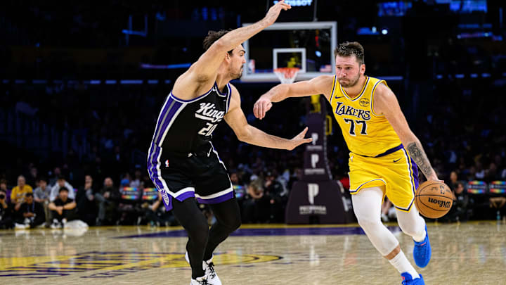 Oct 17, 2025; Los Angeles, California, USA; Los Angeles Lakers guard Luka  Doncic (77) drives the ball against Sacramento Kings forward Dario Saric (20) during the second half at Crypto.com Arena. Mandatory Credit: William Liang-Imagn Images