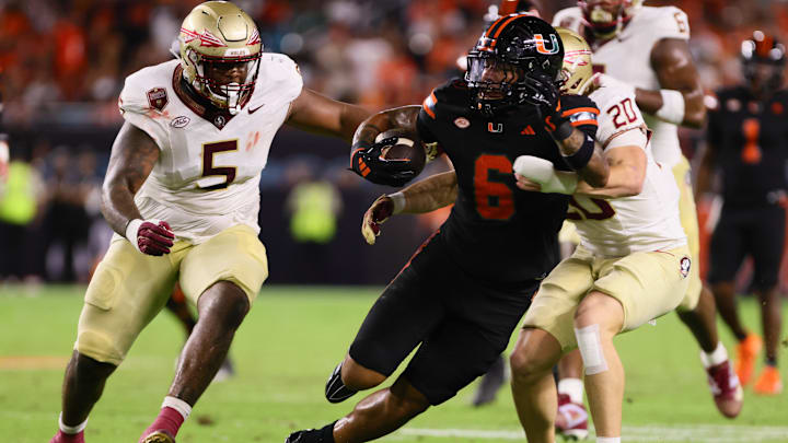 Oct 26, 2024; Miami Gardens, Florida, USA; Miami Hurricanes running back Damien Martinez (6) runs with the football past Florida State Seminoles linebacker Blake Nichelson (20) during the second quarter at Hard Rock Stadium. Mandatory Credit: Sam Navarro-Imagn Images