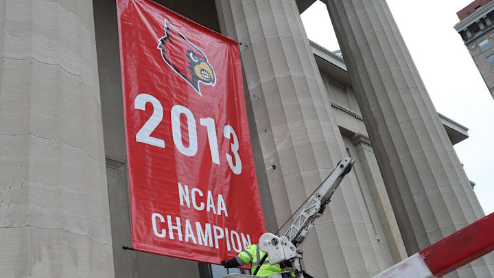 Adam Hightower hangs a replica 2013 NCAA National Championship banner on Louisville Metro Hall