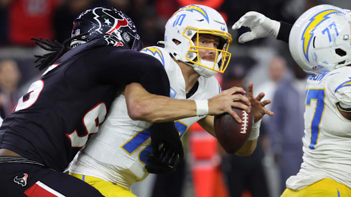 Jan 11, 2025; Houston, Texas, USA; Los Angeles Chargers quarterback Justin Herbert (10) is sacked by Houston Texans defensive end Denico Autry (96) during the third quarter in an AFC wild card game at NRG Stadium. Mandatory Credit: Troy Taormina-Imagn Images