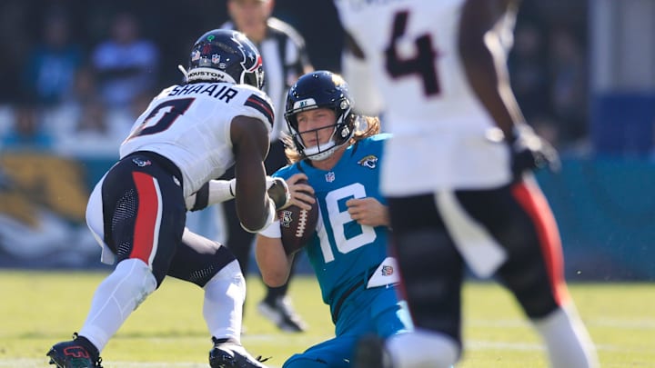 Jacksonville Jaguars quarterback Trevor Lawrence (16) slides for a down as Houston Texans linebacker Azeez Al-Shaair (0) makes a late hit during the second quarter of an NFL football matchup Sunday, 