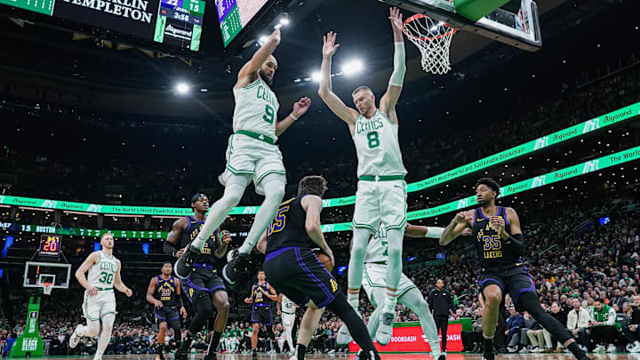 Feb 1, 2024; Boston, Massachusetts, USA; Los Angeles Lakers guard Austin Reaves (15) slips past Boston Celtics center Kristaps Porzingis (8) and guard Derrick White (9) in the first half at TD Garden. Mandatory Credit: David Butler II-Imagn Images