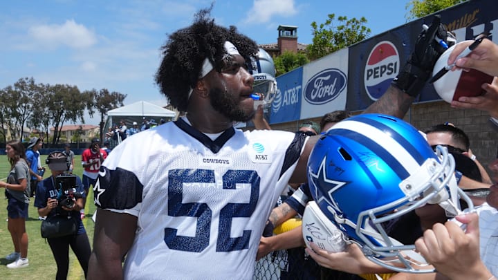 Dallas Cowboys guard Tyler Booker signs autographs during training camp at the River Ridge Fields.