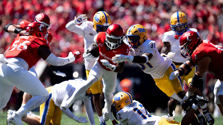 Cincinnati Bearcats wide receiver Tyrin Smith (4) runs for a first down as Pittsburgh Panthers defensive lineman David Ojiegbe (17) and Pittsburgh Panthers linebacker Rasheem Biles (31) tackle him in the second quarter of the College Football game at Nippert Stadium in Cincinnati on Saturday, Sept. 7, 2024.