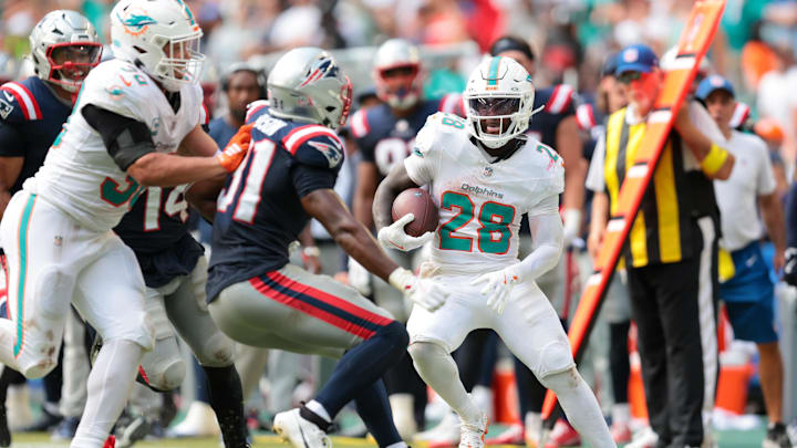 Miami Dolphins running back De'Von Achane (28) steps out of bounds after carrying the football against New England Patriots safety Craig Woodson (31) during the fourth quarter at Hard Rock Stadium.