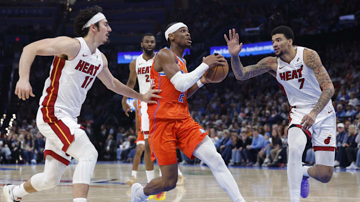 Jan 11, 2026; Oklahoma City, Oklahoma, USA; Oklahoma City Thunder guard Shai Gilgeous-Alexander (2) drives to the basket between Miami Heat guard Jaime Jaquez Jr. (11) and center Kel'el Ware (7) during the second half at Paycom Center. Mandatory Credit: Alonzo Adams-Imagn Images