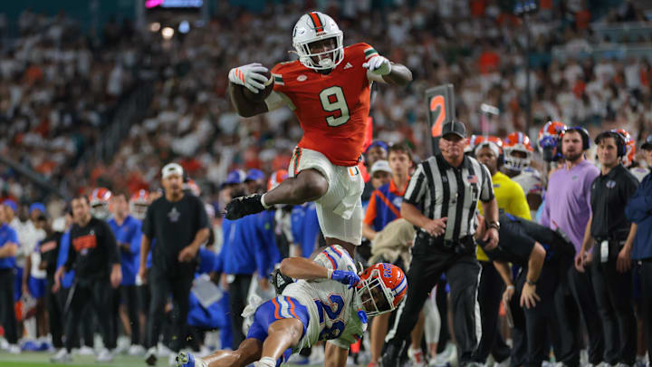 Sep 20, 2025; Miami Gardens, Florida, USA; Miami Hurricanes tight end Elija Lofton (9) hurdles over Florida Gators defensive back Devin Moore (28) during the second quarter at Hard Rock Stadium. Mandatory Credit: Sam Navarro-Imagn Images
