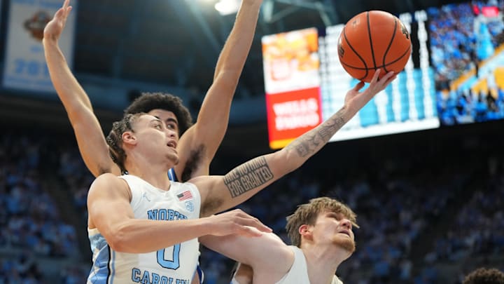 Feb 7, 2026; Chapel Hill, North Carolina, USA; North Carolina Tar Heels guard Kyan Evans (0) shoots as Duke Blue Devils forward Cameron Boozer (12) defends and center Henri Veesaar (13) holds posittion in the second  half at Dean E. Smith Center. Mandatory Credit: Bob Donnan-Imagn Images