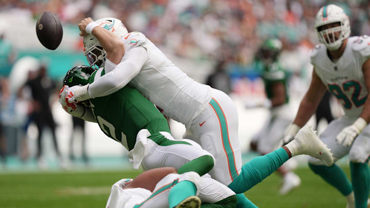 Miami Dolphins linebacker Bradley Chubb, top, and defensive tackle Christian Wilkins, bottom, hit New York Jets quarterback Zach Wilson (2) causing a fumble during the first half of an NFL game at Hard Rock Stadium in Miami Gardens, Dec. 17, 2023.