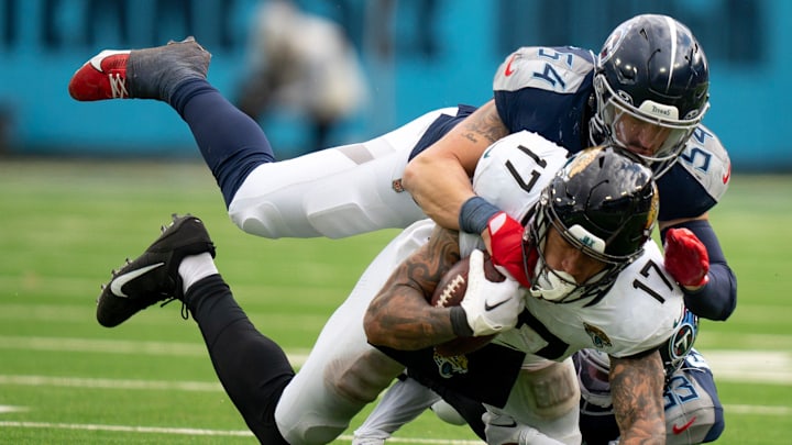 Jacksonville Jaguars tight end Evan Engram (17) is brought down after a catch by Garret Wallow (54) and Tennessee Titans cornerback Eric Garror (33) during their game at Nissan Stadium in Nashville, Tenn., Sunday, Jan. 7, 2024.