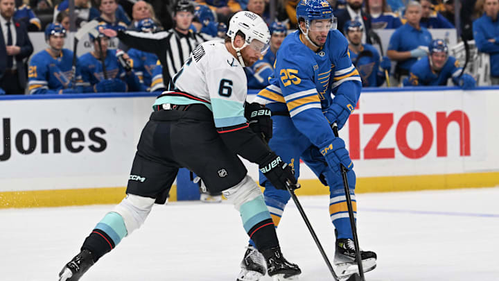 Nov 8, 2025; St. Louis, Missouri, USA; Seattle Kraken defenseman Adam Larsson (6) and St. Louis Blues right wing Jordan Kyrou (25) battle for the puck in the second period at Enterprise Center. Mandatory Credit: Joe Puetz-Imagn Images